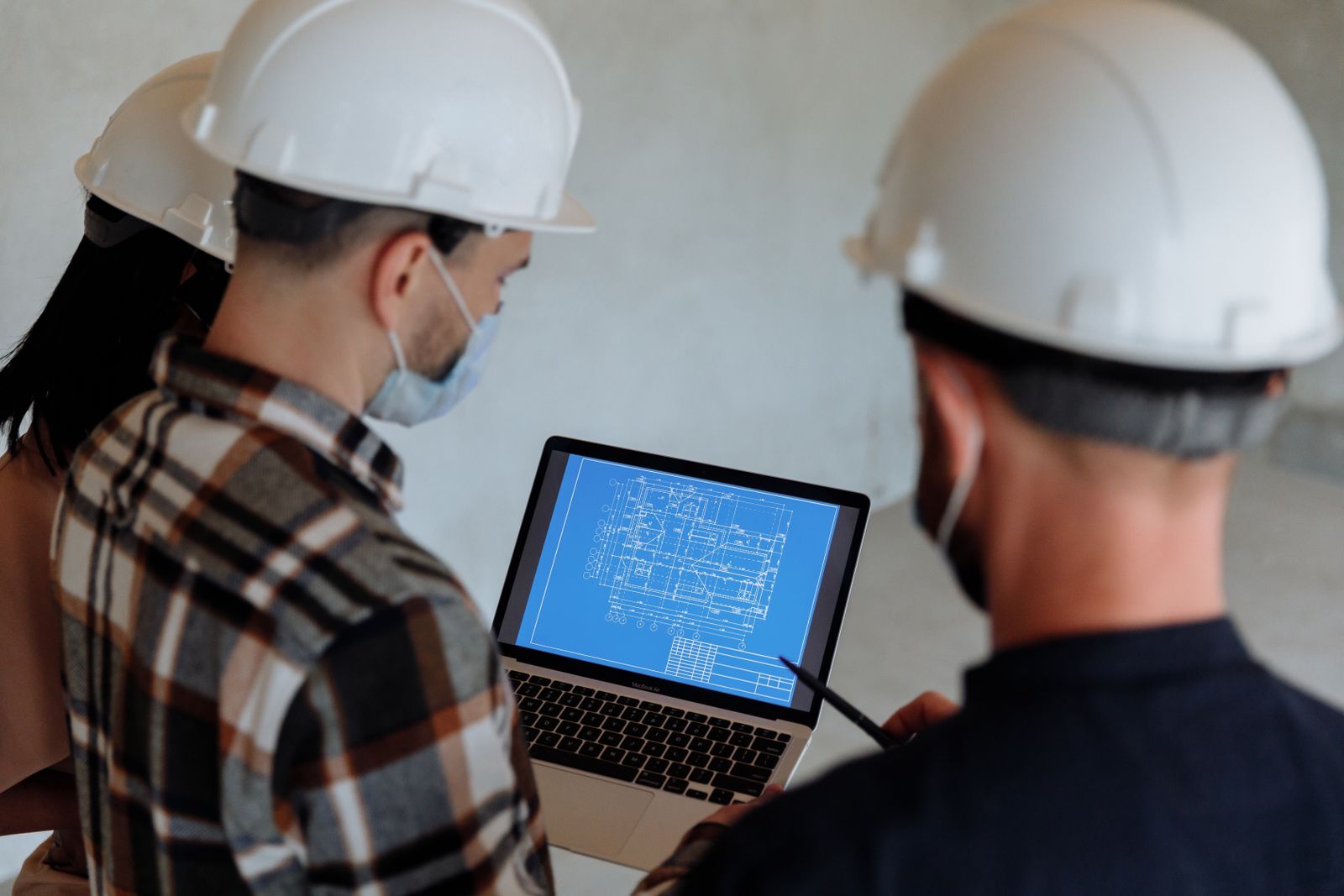 A construction team reviewing paperwork and numbers on a laptop